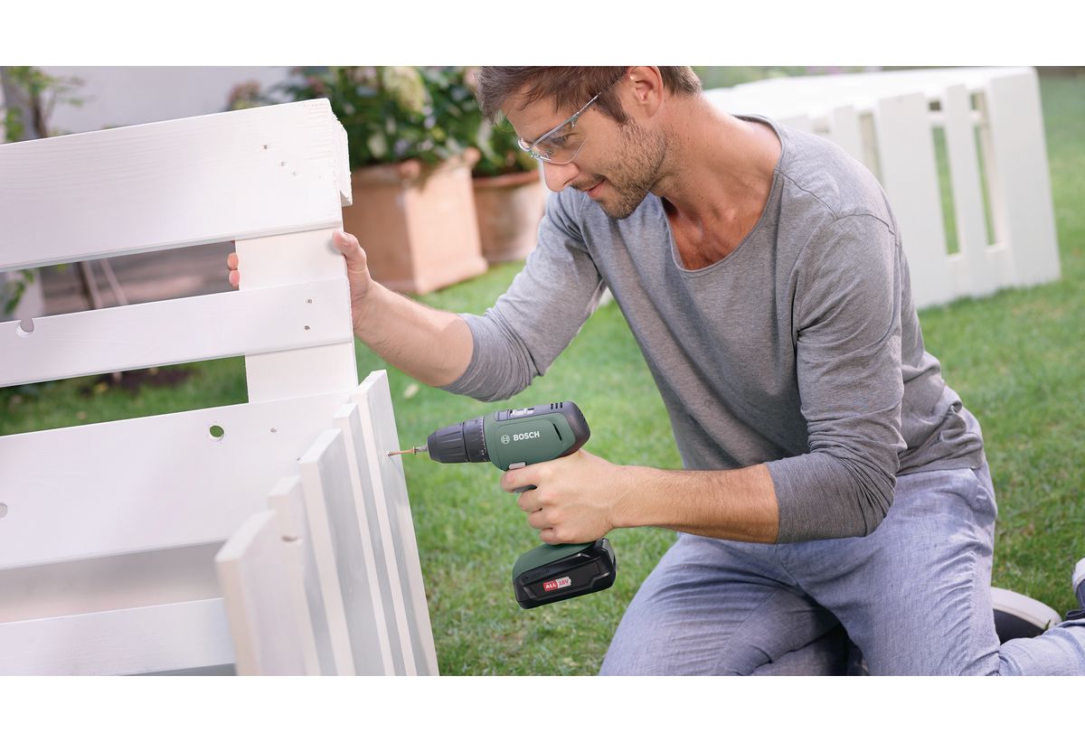 Απεικονίζεται ένας άνδρας να χρησιμοποιεί το δραπανοκατσάβιδο για την αρμολόγηση ενός παγκακιού.